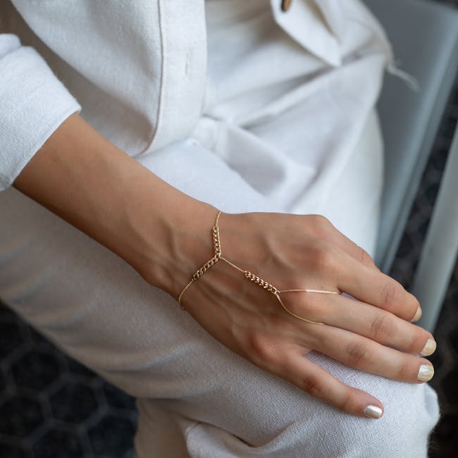 A jeweler using a micro-welder to close a gold chain bracelet on a customer's wrist