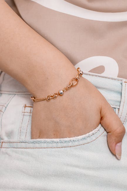 A close-up of a permanent gold-filled bracelet on a wrist next to a laptop keyboard, showing daily wear