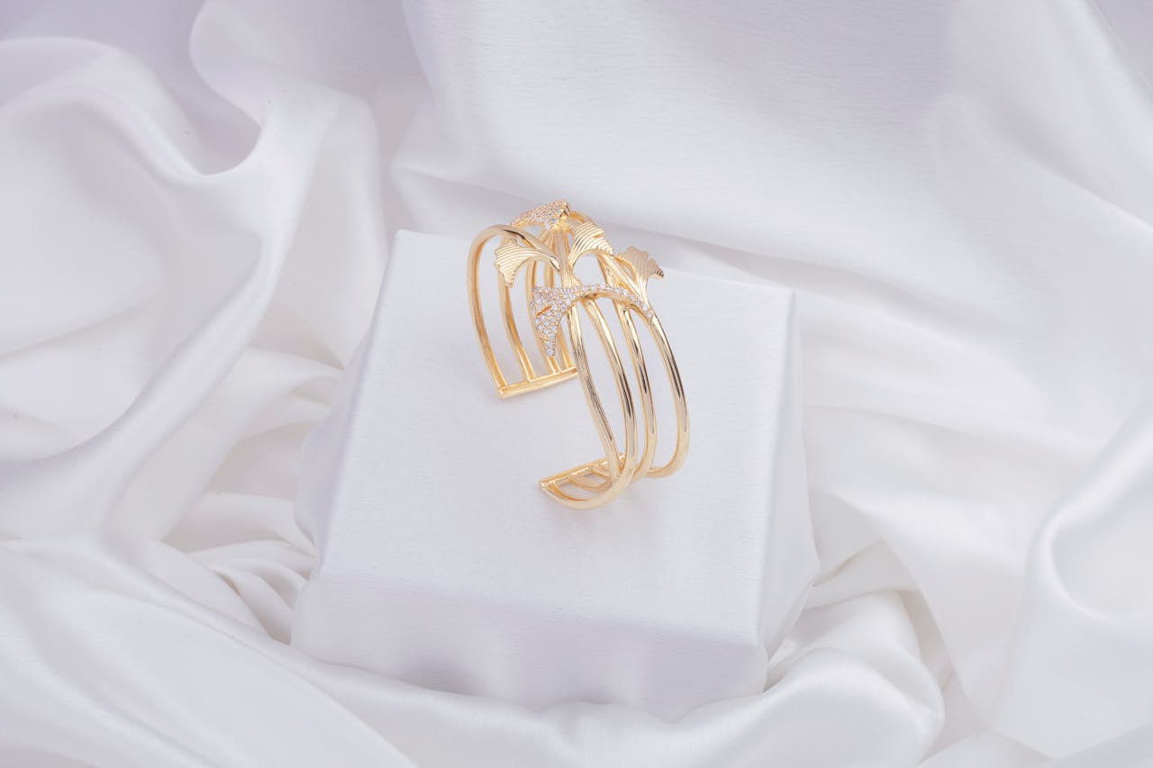 a gold cuff bracelet resting on a neutral fabric showing its open-ended C shape