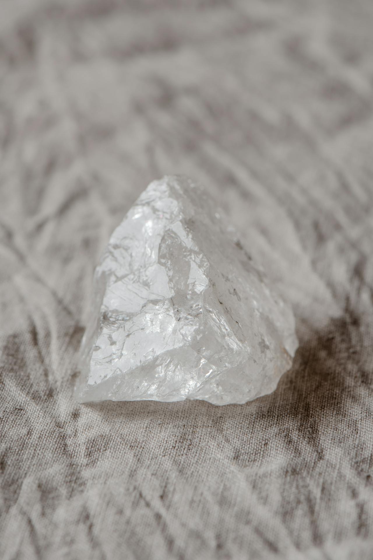 a split image showing raw clear quartz on the left and the same crystal after aura treatment on the right, illustrating the before and after