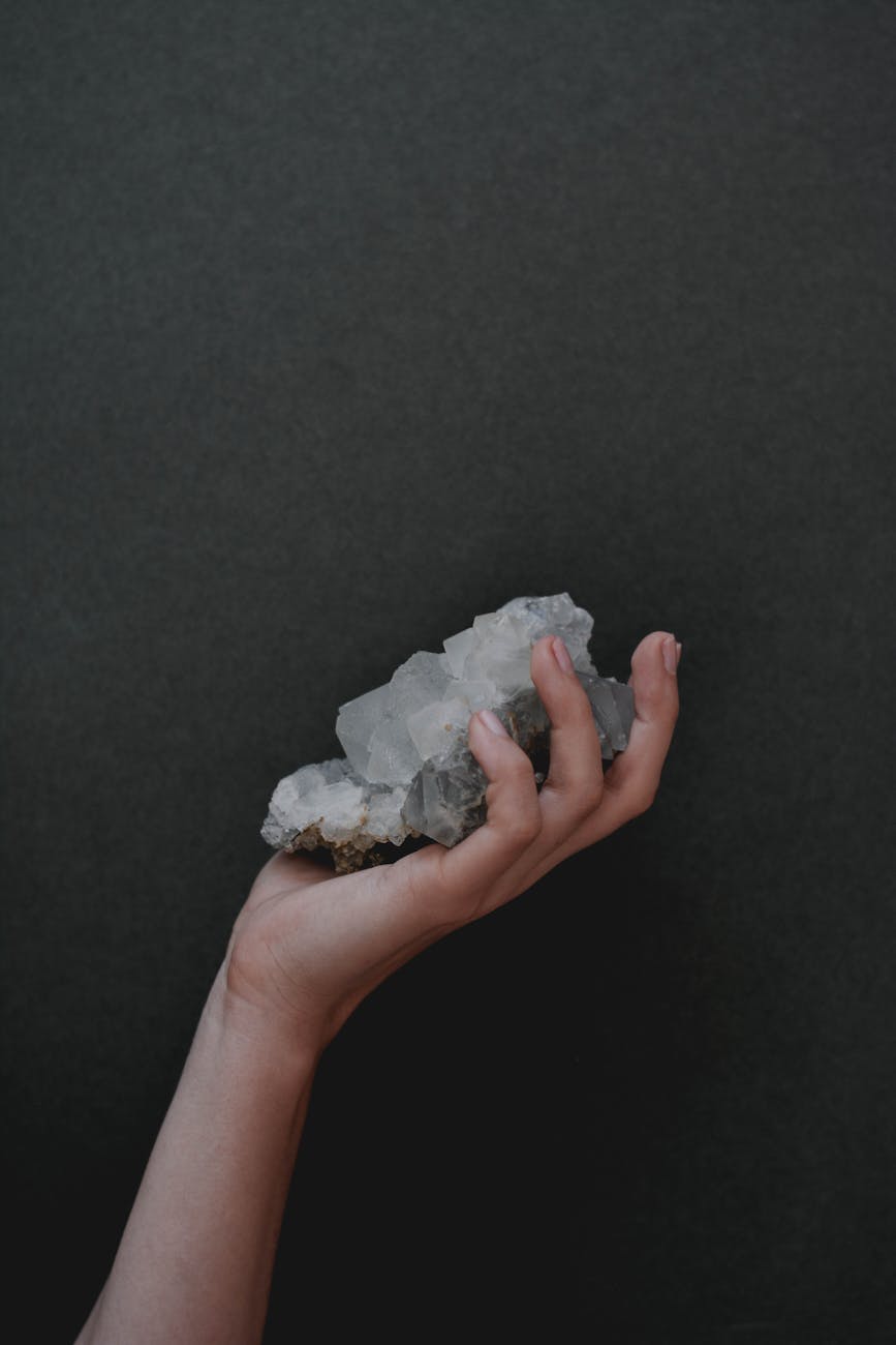 a hand holding an apophyllite crystal cluster up to natural light, showing the transparency and internal inclusions