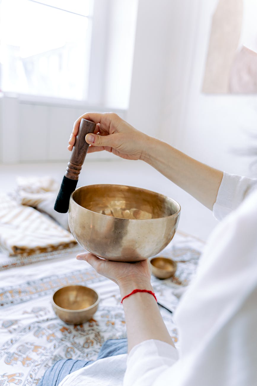 a set of seven brass singing bowls of graduated sizes arranged in a semicircle on a textile mat