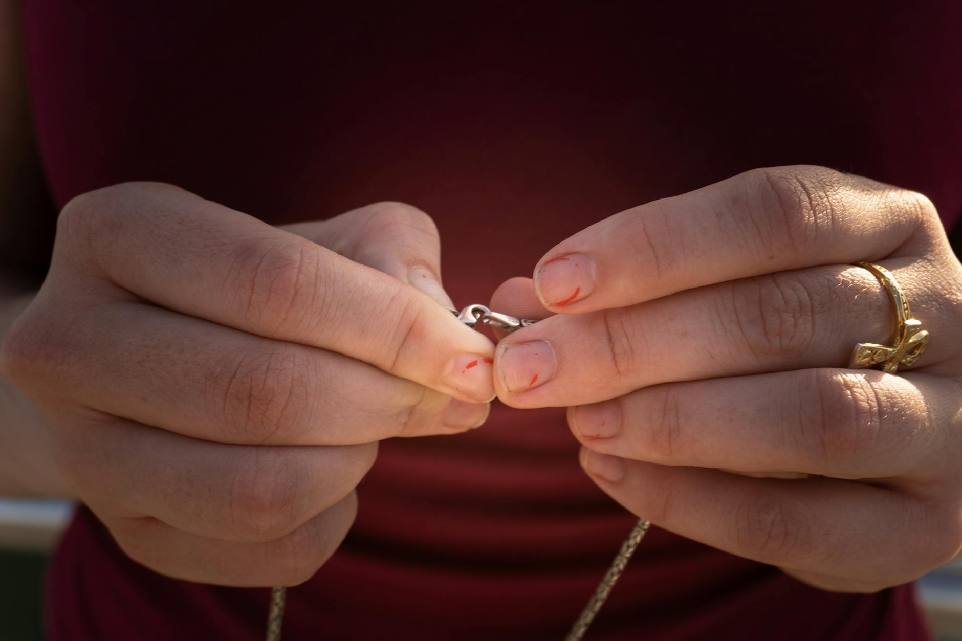 a close-up of a necklace with a broken lobster clasp, showing the gap where the mechanism has separated